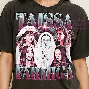 Puede incluir: Camiseta gris oscuro con un diseño gráfico de estilo vintage de Taissa Farmiga. El diseño incluye múltiples imágenes de la actriz y el texto "TAISSA FARMIGA" en una fuente degradada rosa y azul.