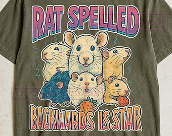 May include: Olive green t-shirt featuring a graphic of several cartoon rats with the text "RAT SPELLED BACKWARDS IS STAR" in a retro style. The design includes pink, blue, and yellow accents.