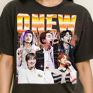 Puede incluir: Camiseta gris oscuro con la palabra "ONEW" en degradado dorado y naranja y una foto de cinco personas. El diseño es de estilo vintage.
