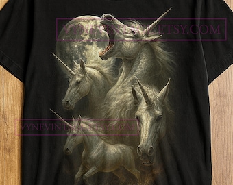 May include: Black t-shirt featuring a detailed illustration of several unicorns with a full moon backdrop. The design showcases the mythical creatures in various poses, with one roaring. The Etsy.com website is visible.
