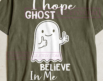 May include: Olive green t-shirt with the text "I hope GHOST Believe In Me" and a white cartoon ghost giving a thumbs up. The shirt is a casual style, suitable for everyday wear.