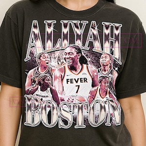May include: Dark gray t-shirt featuring a vintage-style graphic of a basketball player with the name "ALIYAH" above and "BOSTON" below. The player is wearing a "FEVER 7" jersey. The design includes multiple basketball players.