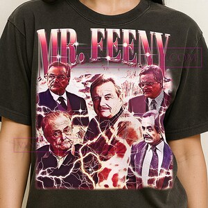 May include: Dark gray t-shirt featuring a graphic of the text "MR. FEENY" above a collage of portraits. The portraits are of men in suits, with a lightning bolt design overlaying the images.