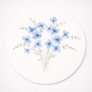 May include: A round, off-white coaster featuring a watercolor painting of delicate blue flowers with green stems and leaves. The floral design is centered on the coaster, creating a simple and elegant aesthetic.