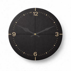 May include: A modern black wall clock with gold-colored numerals and hands. The clock face is divided into four sections. The clock hands are black and the clock has a gold-colored center.