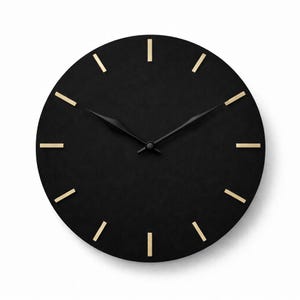 May include: A round, black wall clock with gold hour markers and black hands. The clock has a minimalist design. The clock's diameter is approximately 30 cm. The clock face is uncluttered.