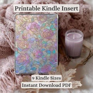 Op de afbeelding: Een Kindle-inzetstuk met een bloemenpatroon in roze, paarse en iriserende tinten. De tekst "Printable Kindle Insert", "9 Kindle Sizes" en "Instant Download PDF" is zichtbaar. Een brandende kaars en gedroogde bladeren staan ook op de foto.