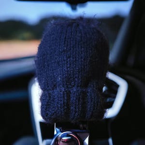 May include: A dark navy blue knit beanie with a ribbed cuff and a textured, fuzzy yarn finish. The hat features a classic stockinette stitch pattern on the main body and a thick, folded brim that provides a structured look to the headwear piece.