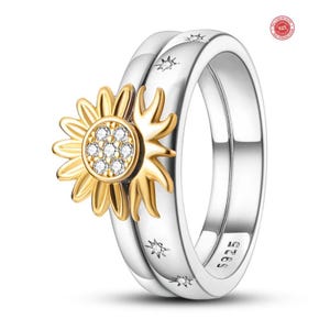 May include: A silver ring set with a gold sunflower design. The sunflower has a center of clear stones. The ring band has star-shaped accents. The ring is a size 9.25.