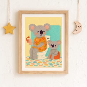 Könnte beinhalten: Gerahmter Kunstdruck mit zwei Cartoon-Koalas in einem Badezimmer. Einer sitzt auf der Toilette, der andere auf einem Töpfchen. Der Hintergrund ist gelb und blau, mit einem bunten gemusterten Boden. Holzrahmen.