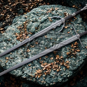 May include: Two silver swords with detailed designs are displayed on a textured grey rock, with fallen leaves scattered around. The swords have dark handles and ornate hilts, suggesting a fantasy theme.