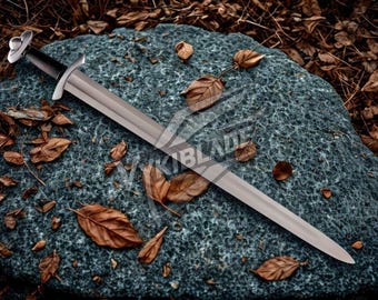 May include: A silver sword with a black handle rests on a textured gray stone, surrounded by fallen brown leaves. The sword has a long, straight blade and a decorative hilt. The image has a rustic, historical theme.