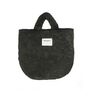 May include: A dark green, fluffy tote bag with a rounded bottom and a single handle. The bag has a small, rectangular tag with the word "uncommon" printed on it. The bag is made of a soft, plush material.