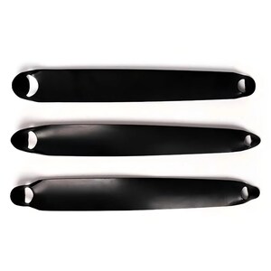 May include: Three elongated, matte black serving trays arranged horizontally. Each tray features a smooth, curved surface with a circular cutout handle on both the left and right ends, providing a consistent, minimalist design across all three pieces.