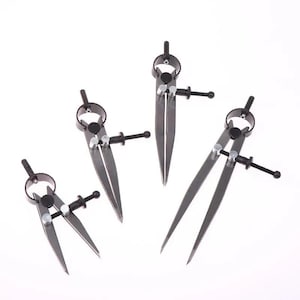 May include: Four black metal compasses with pointed tips are arranged against a white background. Each compass has a circular top, a screw for adjustment, and two legs. The compasses vary slightly in size.