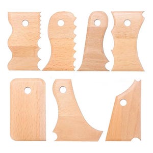 Puede incluir: Colección de siete herramientas de costilla de cerámica de madera en varias formas. Cada herramienta tiene un acabado de madera natural y un pequeño agujero para colgar. Los bordes de las costillas están formados para diferentes efectos en cerámica.