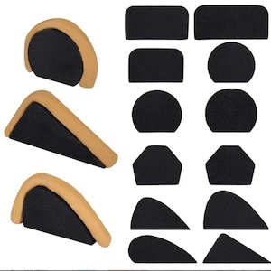 May include: A collection of black and tan foam pads in various shapes. The pads include rectangular, circular, hexagonal, and curved designs. Several wedge-shaped pads with tan tops and black bases are also present.