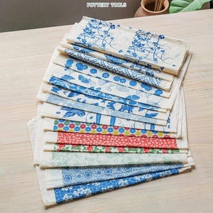 Peut inclure: Une pile de feuilles de papier à motifs avec des motifs floraux et géométriques bleus. Les papiers sont disposés sur une surface en bois clair. Certaines feuilles ont des motifs floraux rouges et multicolores. Le texte "POTTERY TOOLS" est visible en haut.
