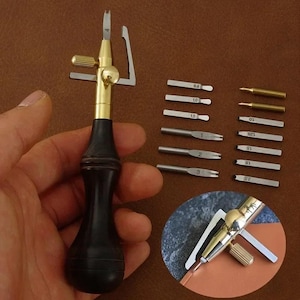 May include: Leathercraft tool set featuring a stitching awl with a black handle and brass accents, along with various interchangeable blades. The set includes blades of different sizes, perfect for leatherworking projects.
