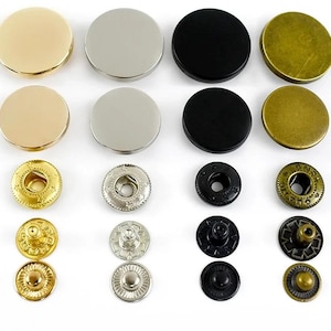 Puede incluir: Un surtido de cierres de presión metálicos en varios colores y acabados. La colección incluye tonos dorados, plateados, negros y latón antiguo. Los cierres de presión son de diferentes tamaños y estilos, adecuados para ropa y manualidades.