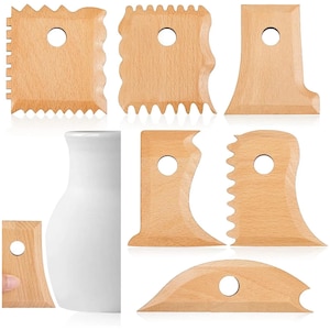 Puede incluir: Un conjunto de herramientas de madera para cerámica de diversas formas, incluyendo bordes cuadrados, curvos y dentados. Cada herramienta tiene un agujero circular para colgar. También se ve un jarrón de cerámica blanco.