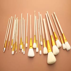 May include: A collection of various paint brushes with light-colored wooden handles and gold-toned metal ferrules. The brushes feature soft, white bristles in a range of sizes, from thin, pointed tips to large, wide, and rounded brush heads.