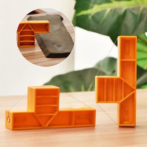 Könnte beinhalten: Orangefarbene Eckklemmen aus Kunststoff mit Draht, für Holzbearbeitung oder Heimwerkerprojekte. Die Klemmen haben ein rechtwinkliges Design mit Innenstützen, auf einer Holzoberfläche.