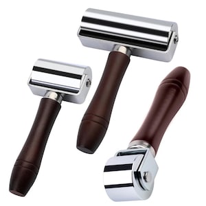 May include: Three metal and wood hand rollers. The rollers have a shiny, silver finish and are attached to dark brown wooden handles. The handles are smooth and rounded. The rollers are designed for various crafting and industrial applications.
