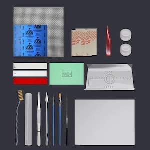 Può includere: Un kit per la creazione di gioielli con vari strumenti e forniture. Include carta vetrata, panni per lucidatura, pennelli, pinzette, un righello e piccoli contenitori. Il kit presenta anche un oggetto rosso a forma di goccia e una scheda rettangolare bianca.