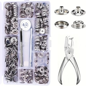 May include: A clear plastic organizer filled with various silver metal snap fasteners, tools, and a silver metal hole punch. The snaps are in different sizes and styles. The tools include a setting tool and a punch tool.