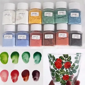 Puede incluir: Un conjunto de doce frascos de vidrio cuadrados llenos de pigmentos en polvo de colores, cada uno con tapa blanca y una etiqueta con texto en chino y los números 520 580C. Debajo hay ocho muestras de color y un vaso con una planta pintada.