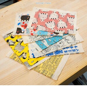 Könnte beinhalten: Eine Sammlung farbenfroher Stoffquadrate mit verschiedenen Mustern, darunter Elefanten, Katzen, Zebras und Cartoon-Illustrationen. Einige Quadrate zeigen Text in englischer und asiatischer Sprache. Der Text "POTTERY TOOLS" ist sichtbar.