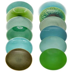 May include: A collection of twelve round ceramic plates arranged in two vertical columns. The plates feature various shades of green, blue, and teal, with diverse finishes including glossy, matte, speckled, and textured surfaces in different tones.