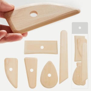 May include: A set of light-coloured wooden pottery ribs and scrapers in various shapes, including curved, rectangular, and teardrop forms. Each tool features a circular hole for gripping, and one long, narrow tool has a serrated edge.
