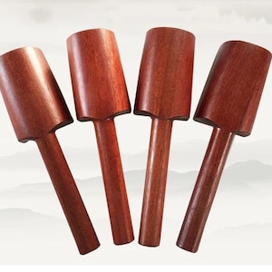 Puede incluir: Cuatro cucharas de madera idénticas con un acabado marrón rojizo profundo. Cada cuchara presenta una cabeza cilíndrica y un mango largo y recto. La veta de la madera es visible en la superficie lisa de cada herramienta, mostrando una textura.