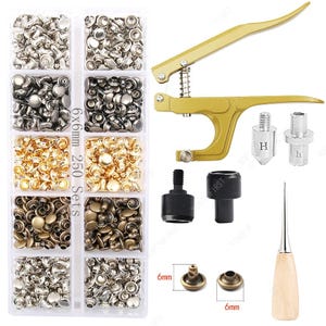 May include: A set of metal rivets in various colors, a gold-colored rivet press, and tools. The rivets are in a clear plastic organizer. The text on the organizer reads "6x6mm 250 Sets". A leathercrafting tool is also included.