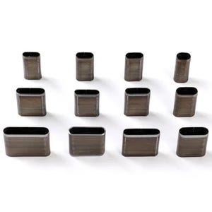 Puede incluir: Una colección de doce punzones de metal ovalados para artesanía en cuero. Los punzones están dispuestos en tres filas de cuatro, cada uno con un cuerpo rectangular y un interior hueco. El metal tiene un acabado oscuro y mate.