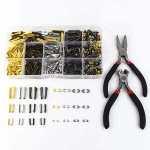 May include: A clear plastic organiser containing an assortment of metal fasteners in gold, silver, and black. Two pliers with black handles and red detailing are also visible. The fasteners are of various shapes, ideal for jewellery making or crafts.