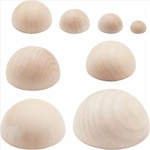 May include: A collection of seven unfinished wooden half-spheres arranged in varying sizes. Each piece features a smooth, light-colored natural wood grain texture with a rounded dome shape and a flat base, showcasing different diameters across the set.