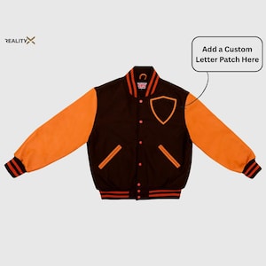 Może przedstawiać: Brązowo-pomarańczowa kurtka typu varsity z naszywką w kształcie tarczy i napisem "Add a Custom Letter Patch Here". Kurtka ma pomarańczowe rękawy, czarny korpus oraz czerwono-czarne paski na mankietach i kołnierzu.
