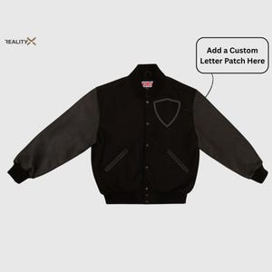 May include: Black varsity jacket with gray sleeves. Features a shield-shaped patch and the text "Add a Custom Letter Patch Here". Includes a small British flag patch near the collar.