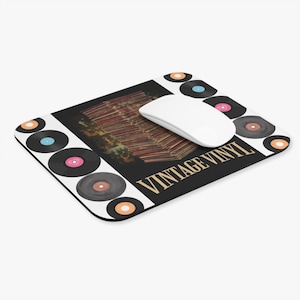 Puede incluir: Alfombrilla de ratón rectangular con fondo negro y las palabras "VINTAGE VINYL" en dorado. La alfombrilla presenta una pila de discos de vinilo y está rodeada de gráficos de discos de vinilo y un ratón de ordenador blanco.