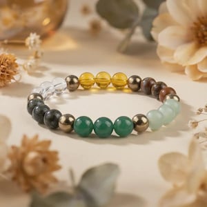 Könnte beinhalten: Ein Armband mit bunten Edelsteinen. Das Armband besteht aus transparenten, dunkelgrünen, goldenen, gelben, braunen und hellgrünen Perlen. Die Perlen sind aufgereiht und bilden ein modisches Accessoire. Der Umfang des Armbands beträgt ca. 17 cm.