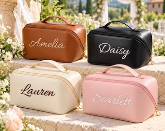 May include: Four rectangular cosmetic bags with top handles and gold-tone zippers. The brown bag features the name Amelia, the black bag features Daisy, the cream bag features Lauren, and the pink bag features the name Scarlett in script.