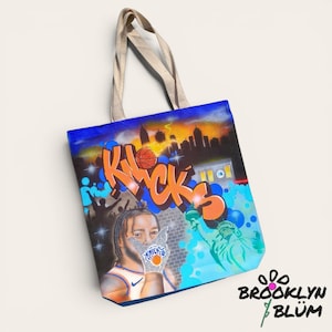 Pode incluir: Uma sacola de lona com um design vibrante feito com aerógrafo, exibindo a palavra KNICKS em letras de grafite laranja. O gráfico inclui uma bola de basquete, o horizonte de uma cidade, uma pessoa vestindo uma camisa, a Estátua da Liberdade e um metrô.