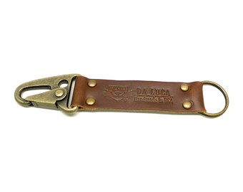May include: A brown leather keyring with a brass hook and a brass ring. The leather strap has the text "DA LUCA Handmade in USA" embossed on it.