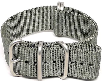 Könnte beinhalten: Ein graues Nylon-Uhrenarmband mit silberner Hardware. Das Armband hat eine Schließe und zwei Schlaufen.