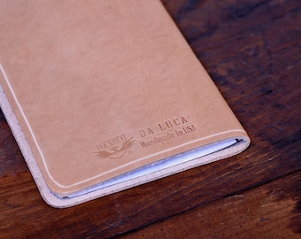 May include: A tan leather notebook with the text "DA LUCA Handmade in USA" embossed on the cover.