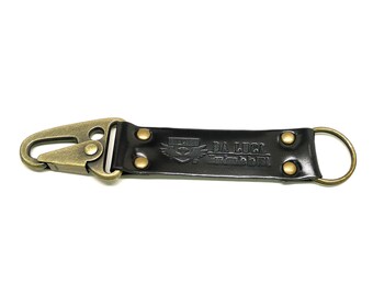 May include: A black leather keyring with a gold metal hook and a gold metal ring. The keyring has the text "DA LUCE" and "Firenze, Italy" embossed on it.