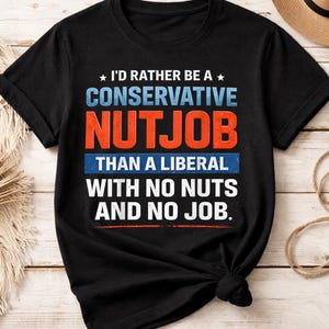 Puede incluir: Camiseta negra con el texto "I'D RATHER BE A CONSERVATIVE NUTJOB THAN A LIBERAL WITH NO NUTS AND NO JOB" en letras blancas, azules y naranjas. La camiseta tiene cuello redondo y mangas cortas.
